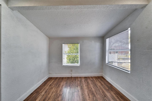 empty room with dark wood-type flooring and a textured ceiling