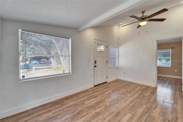 entrance foyer featuring vaulted ceiling, ceiling fan, a textured ceiling, and light hardwood / wood-style floors