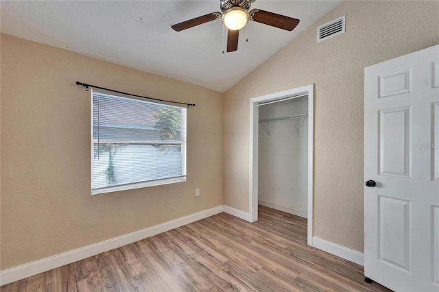 unfurnished bedroom featuring lofted ceiling, light hardwood / wood-style floors, a closet, and ceiling fan