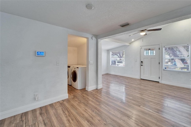 interior space with washing machine and clothes dryer, vaulted ceiling, a textured ceiling, light wood-type flooring, and ceiling fan