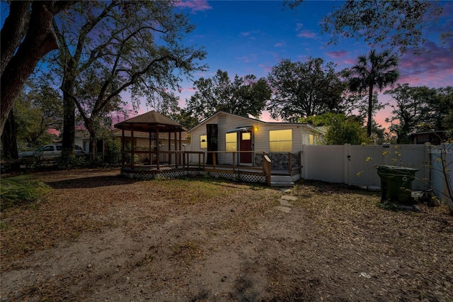 back house at dusk with a gazebo and a deck