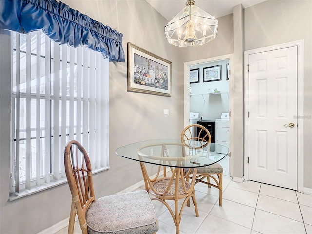 dining space featuring tile patterned flooring, a notable chandelier, and washing machine and clothes dryer