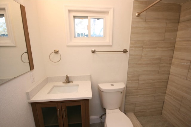 bathroom with tiled shower, vanity, and toilet