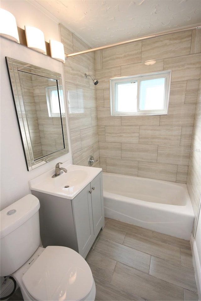 full bathroom featuring tiled shower / bath, vanity, and toilet