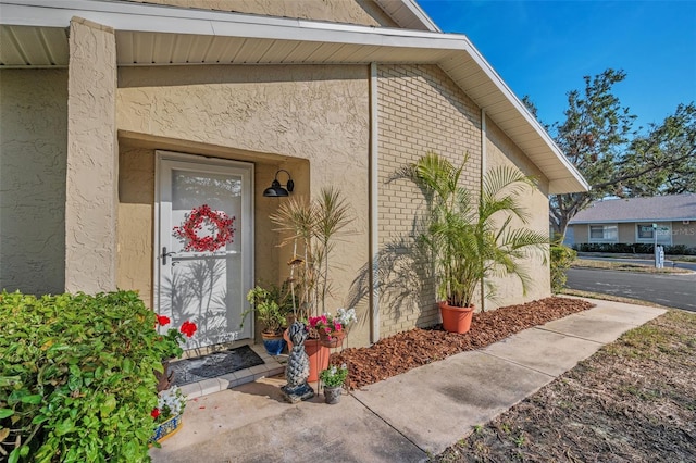 property entrance with brick siding and stucco siding