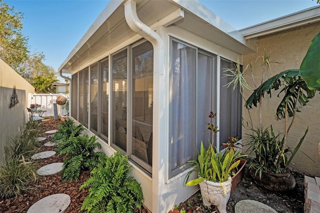 view of home's exterior with fence and a sunroom