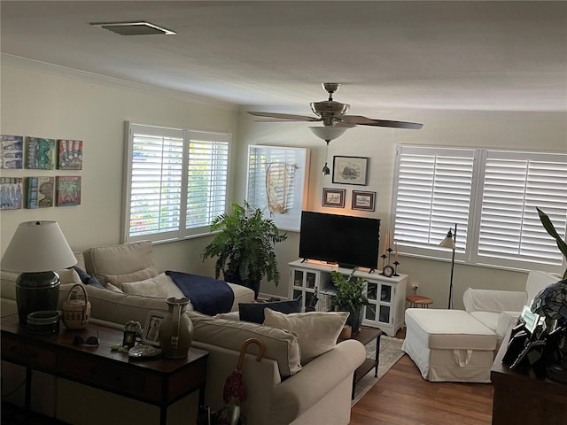 living room featuring visible vents, ornamental molding, ceiling fan, and wood finished floors