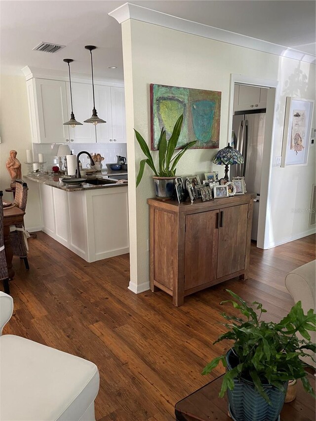 kitchen featuring visible vents, dark wood-style flooring, a sink, white cabinetry, and tasteful backsplash