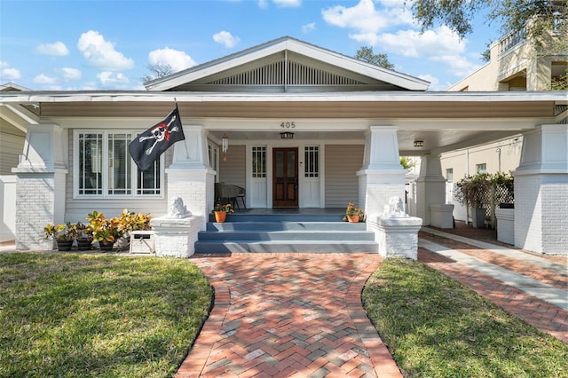 entrance to property with a yard and covered porch