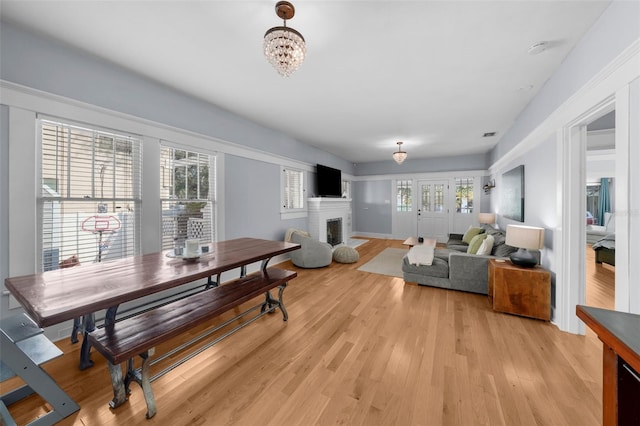 living room with a notable chandelier, a fireplace, and light wood-type flooring