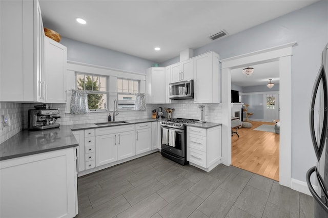 kitchen with tasteful backsplash, white cabinetry, appliances with stainless steel finishes, and sink