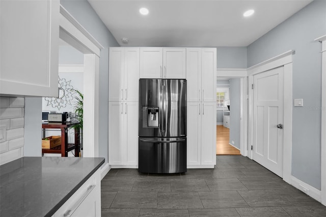 kitchen featuring white cabinetry, dark stone countertops, and stainless steel refrigerator with ice dispenser