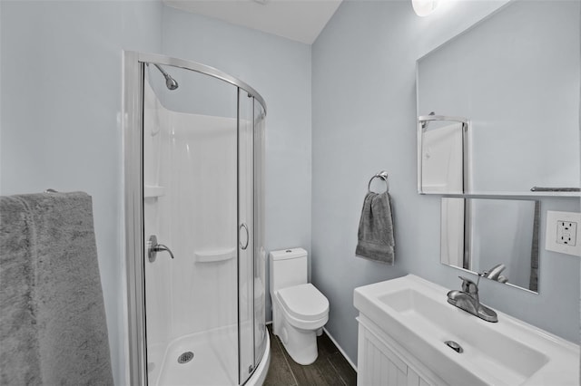 bathroom with hardwood / wood-style floors, vanity, toilet, and walk in shower