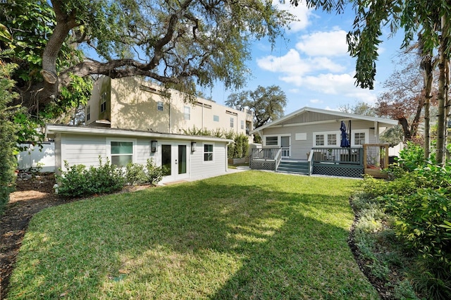 rear view of house with a yard, a deck, and french doors