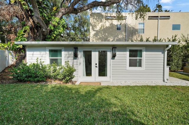 rear view of property featuring a lawn and french doors