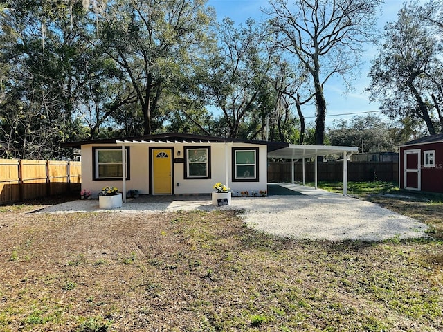 view of front of house with a carport, a shed, and a front lawn