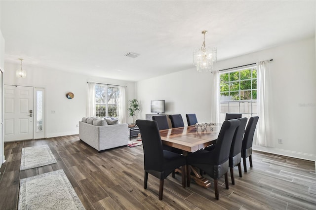 dining space featuring dark wood-type flooring and a notable chandelier