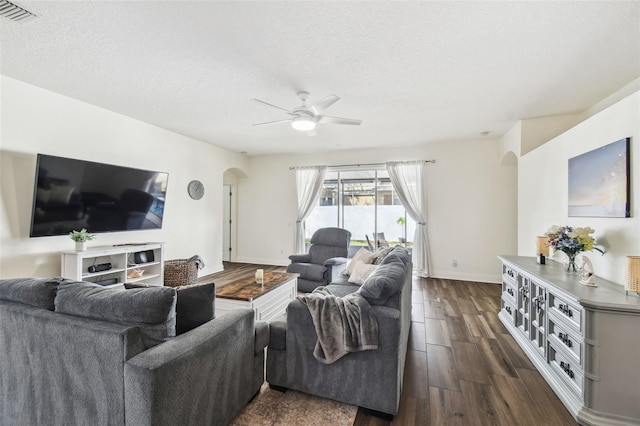 living room with ceiling fan, dark hardwood / wood-style flooring, and a textured ceiling