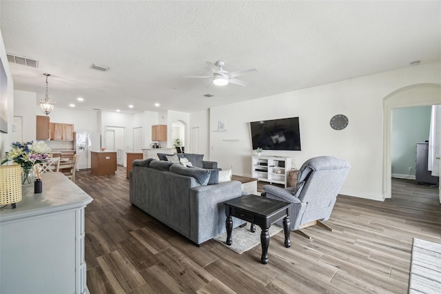 living room featuring hardwood / wood-style floors, a textured ceiling, and ceiling fan