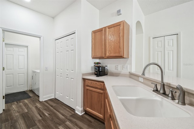 kitchen featuring sink, washer and clothes dryer, and dark hardwood / wood-style floors