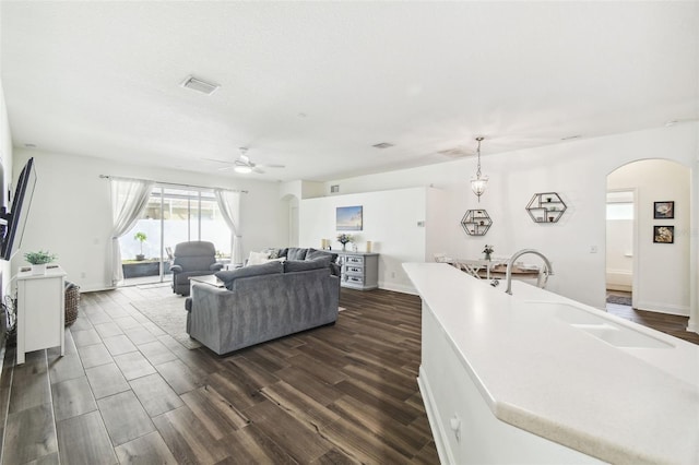 living room with dark wood-type flooring, ceiling fan, sink, and a textured ceiling