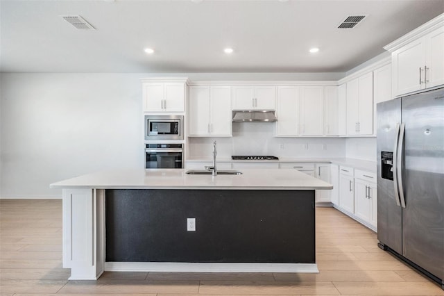 kitchen featuring sink, an island with sink, stainless steel appliances, light hardwood / wood-style floors, and white cabinets