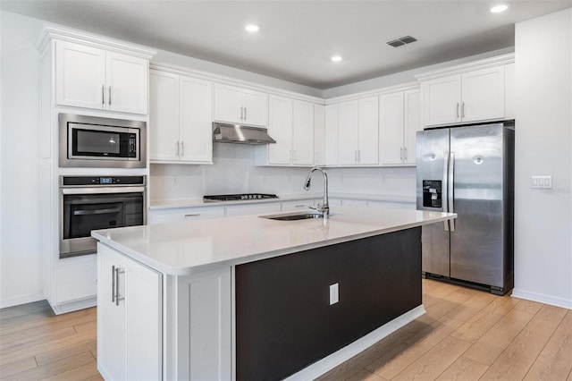 kitchen featuring a kitchen island with sink, sink, stainless steel appliances, and white cabinets