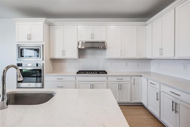 kitchen featuring appliances with stainless steel finishes, light stone countertops, sink, and white cabinets