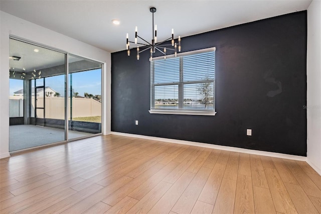 spare room with light hardwood / wood-style flooring and a notable chandelier