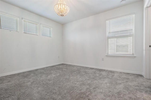 spare room featuring carpet and an inviting chandelier