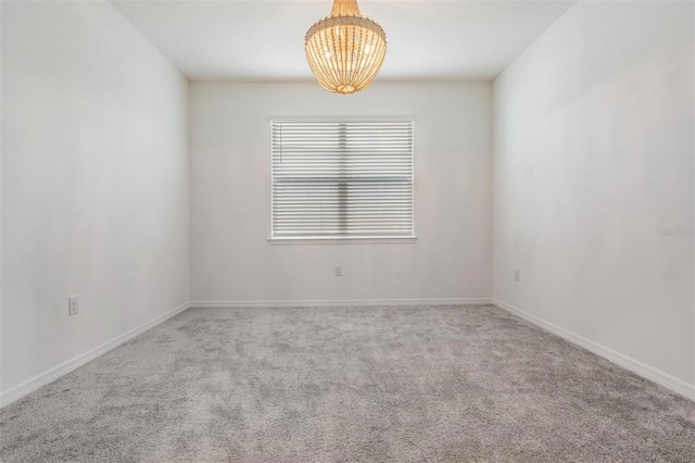 carpeted spare room with a notable chandelier