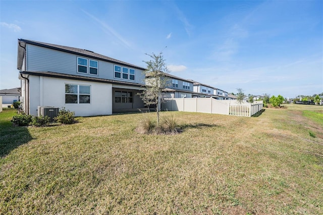 rear view of property with a yard and central air condition unit