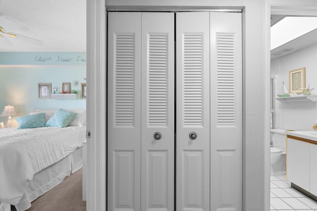 bedroom featuring light tile patterned flooring, connected bathroom, and a closet