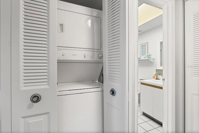 laundry area featuring light tile patterned flooring and stacked washer and dryer