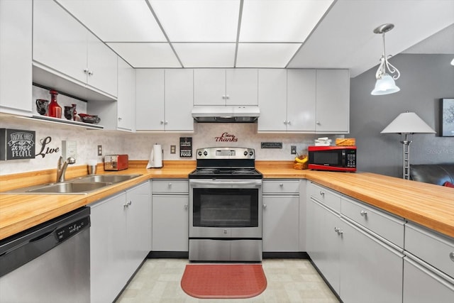 kitchen with hanging light fixtures, wooden counters, white cabinets, and stainless steel appliances