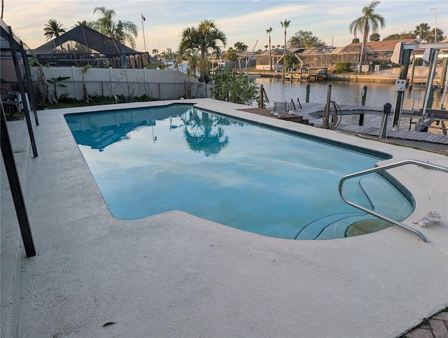 pool at dusk featuring a water view