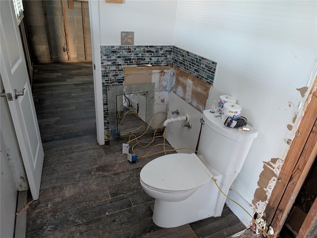 bathroom with hardwood / wood-style flooring, toilet, and tile walls