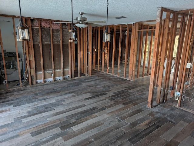 misc room with ceiling fan, a textured ceiling, and dark hardwood / wood-style flooring