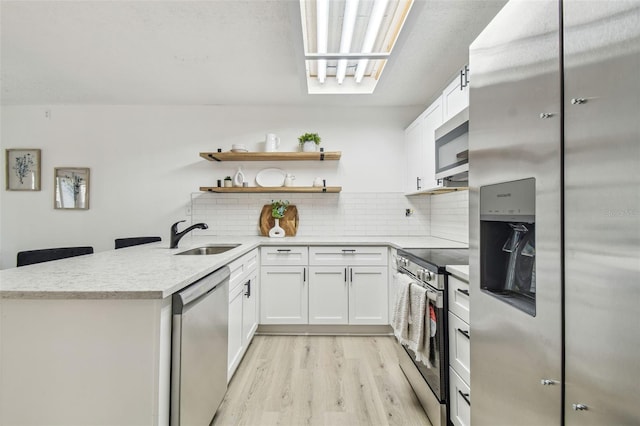 kitchen featuring sink, backsplash, white cabinets, and appliances with stainless steel finishes