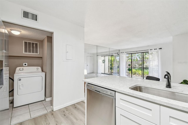 kitchen featuring washer / clothes dryer, stainless steel dishwasher, sink, and white cabinets