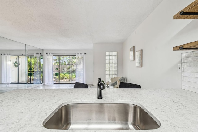 kitchen featuring light stone countertops, sink, and a textured ceiling