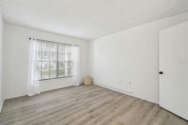 spare room featuring a textured ceiling and light wood-type flooring