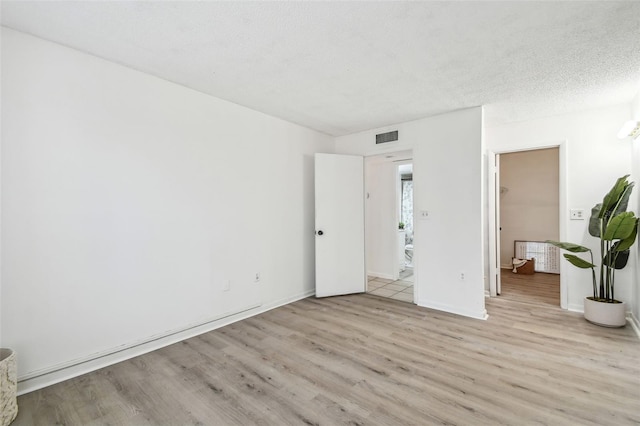 unfurnished bedroom featuring a textured ceiling and light hardwood / wood-style flooring