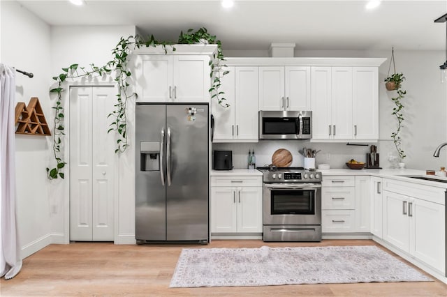 kitchen featuring white cabinetry, stainless steel appliances, sink, and light hardwood / wood-style flooring