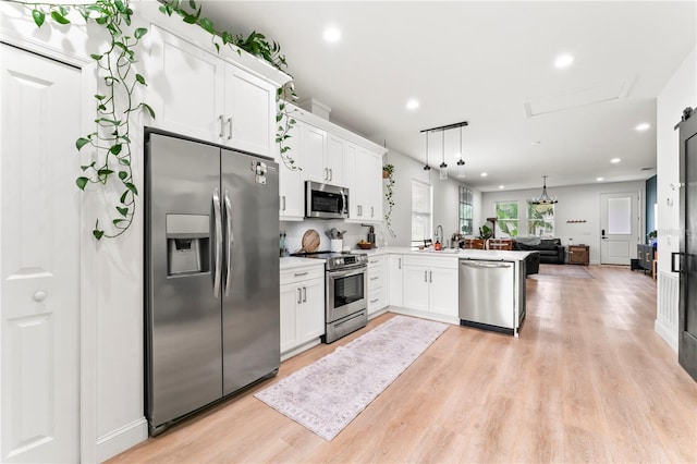 kitchen with pendant lighting, kitchen peninsula, white cabinets, and appliances with stainless steel finishes