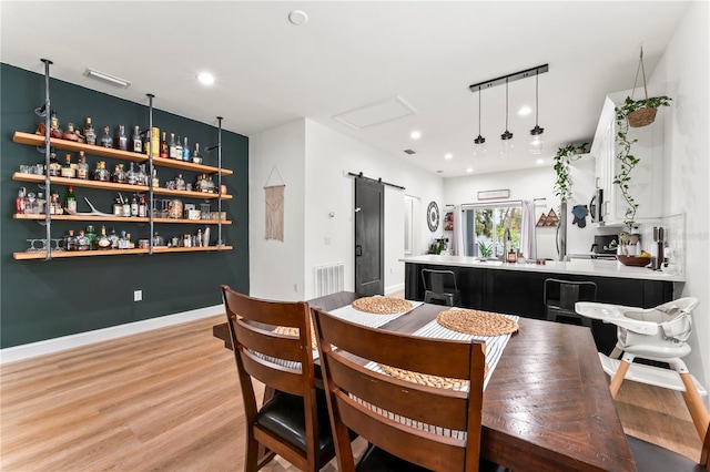 dining room with a barn door and light hardwood / wood-style flooring