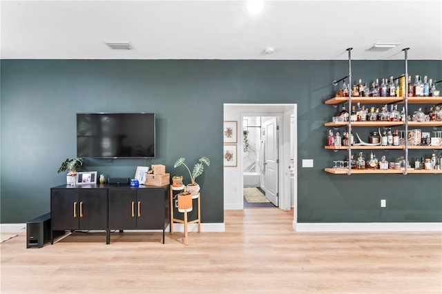 living room featuring bar and light hardwood / wood-style floors