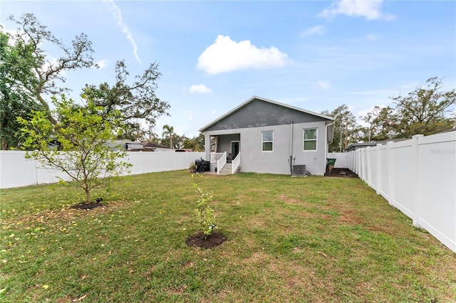 rear view of property featuring a yard and central air condition unit