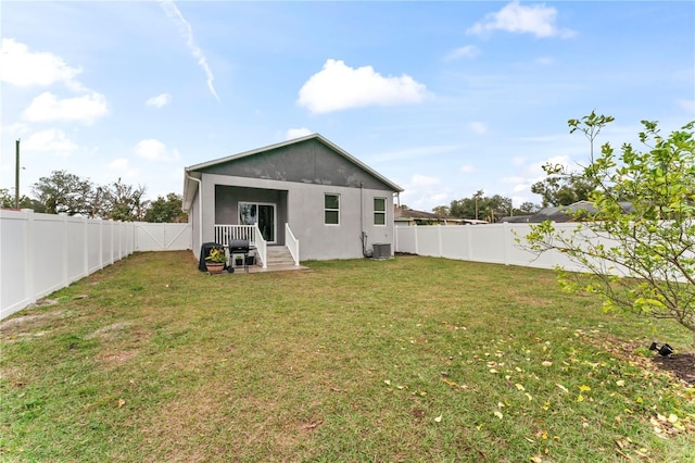 rear view of house with central AC unit and a lawn