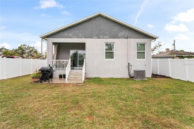 rear view of house with cooling unit and a lawn